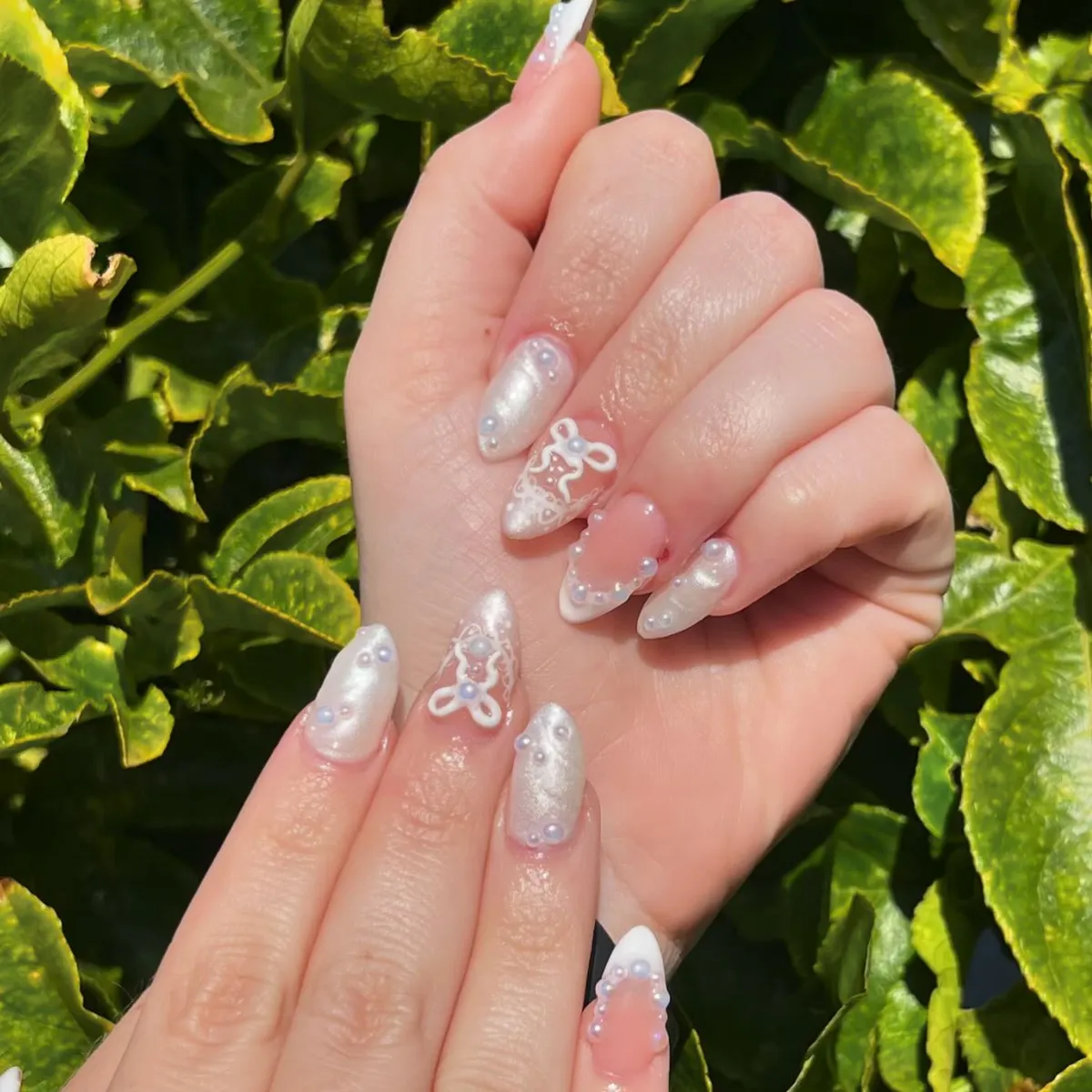 Pearly white nails with bow motifs and pearl-like studs