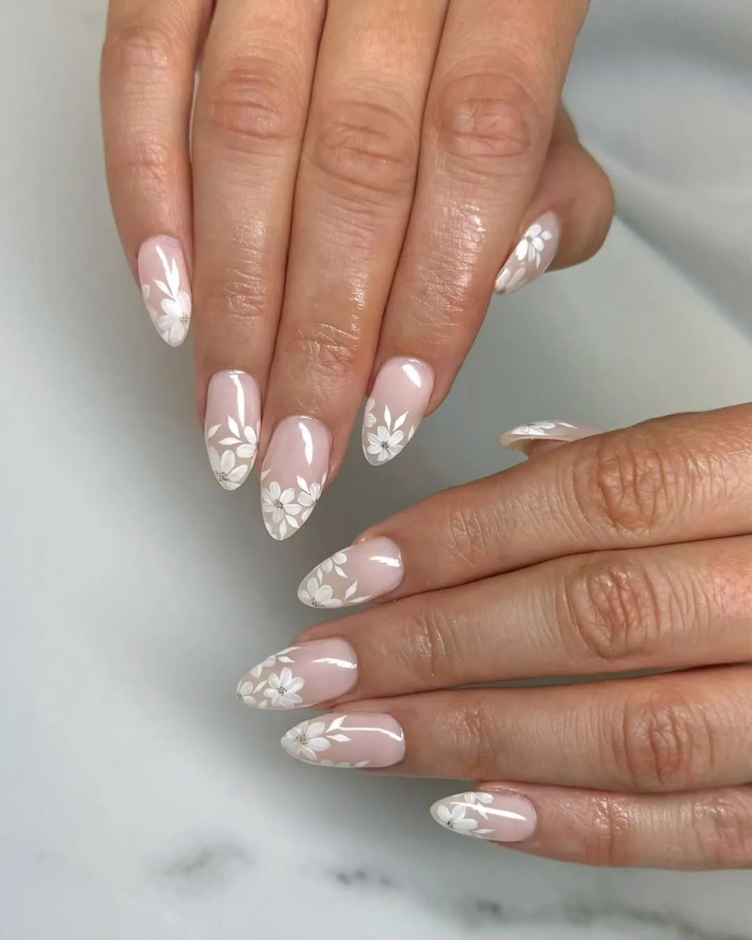 Pale pink almond nails with white floral clusters
