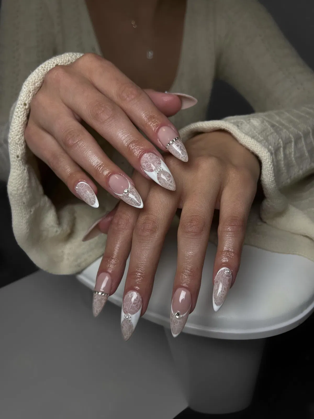 Nude stiletto nails with white tips and lace-like detailing