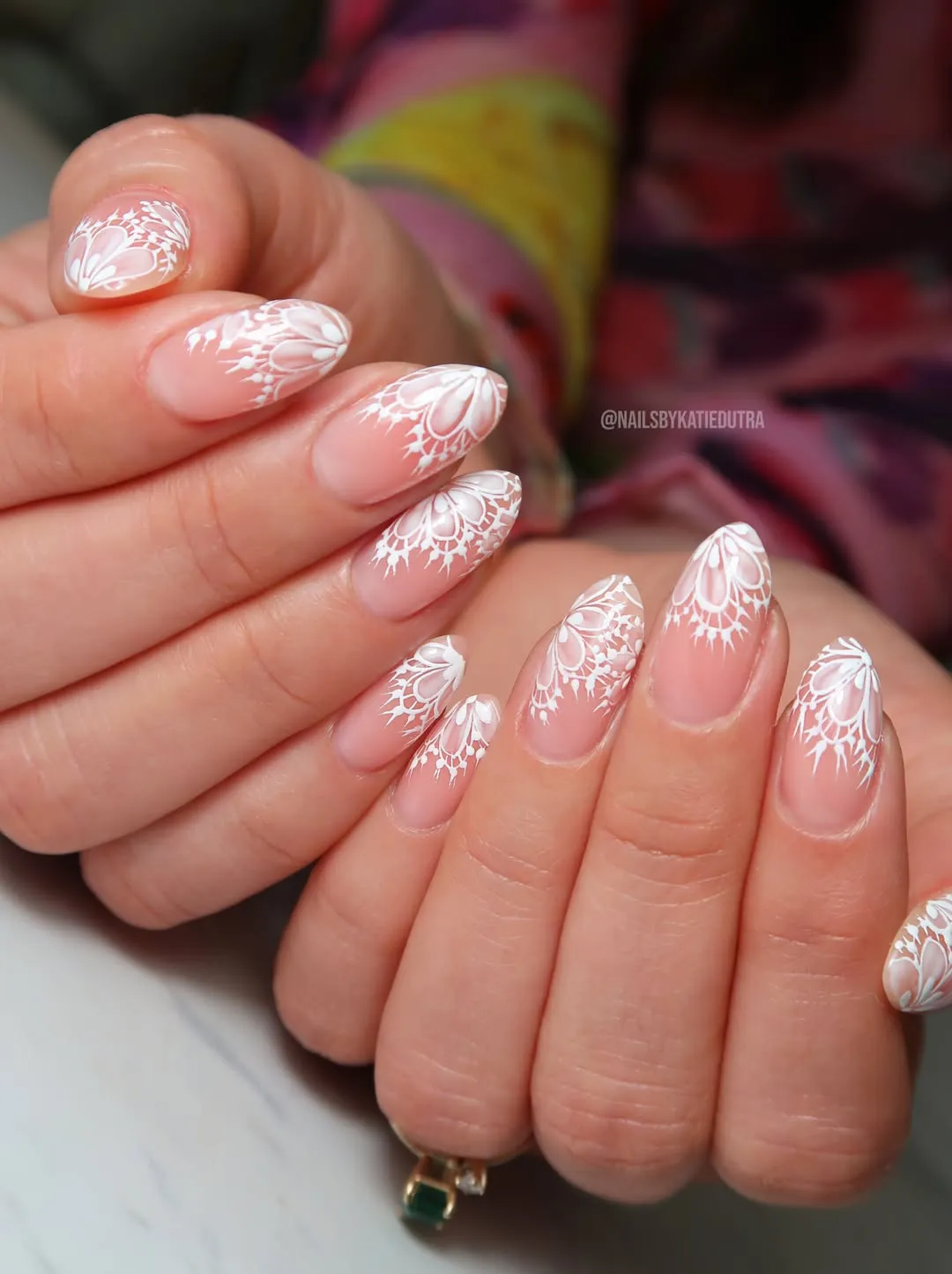 White lace-style tip art on sheer nude almond nails