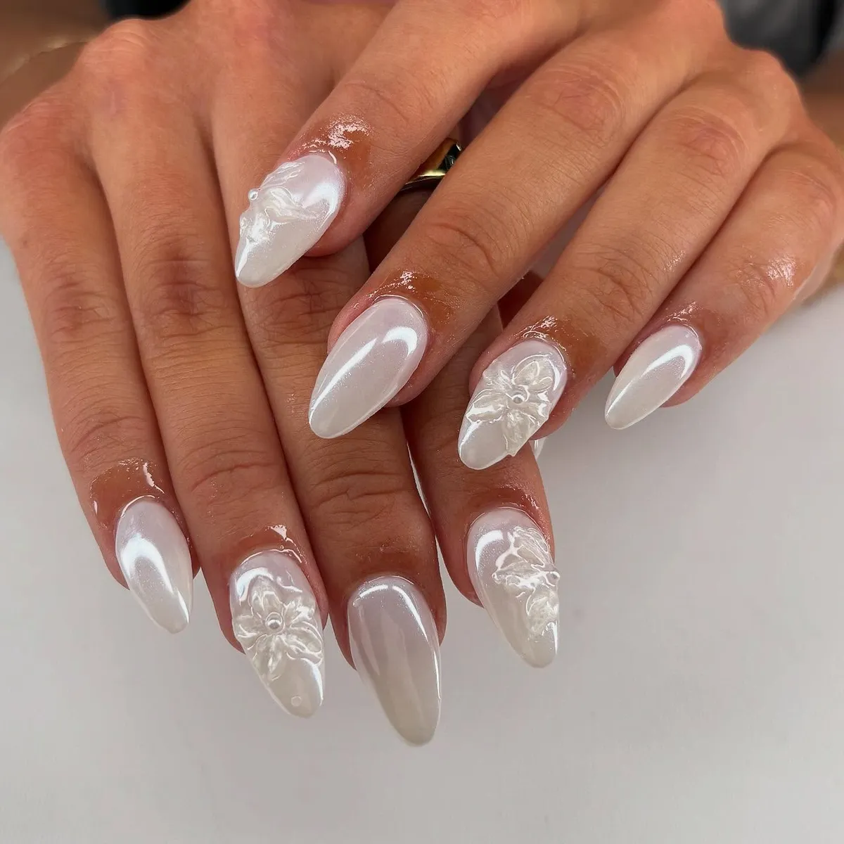 Pearly white almond nails with raised floral detailing