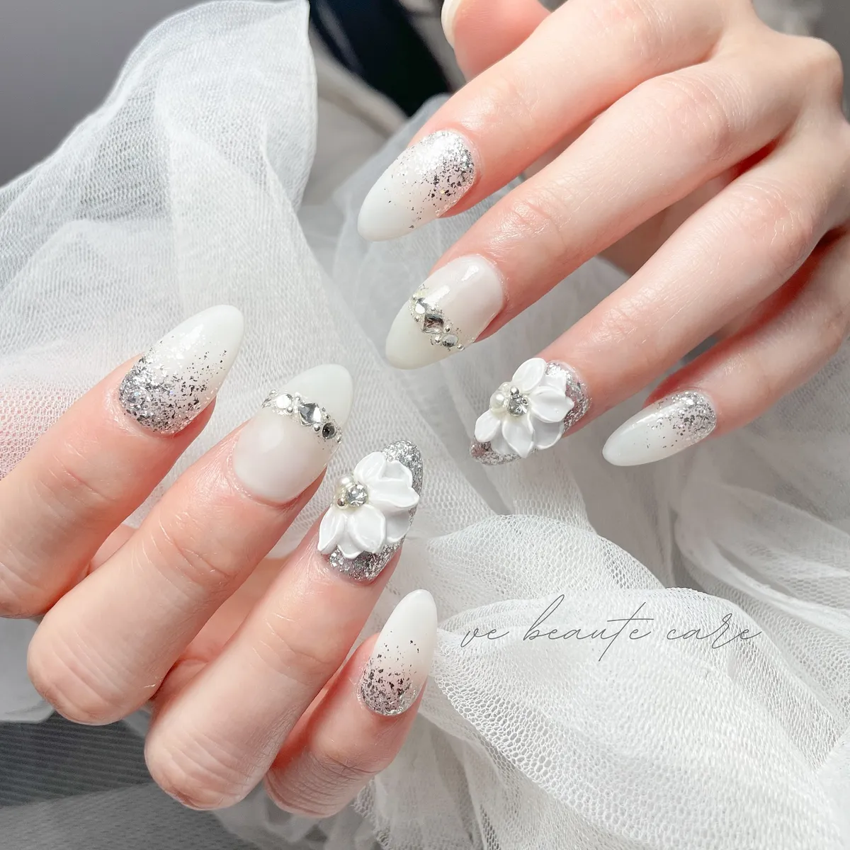 Milky white almond nails with silver glitter and 3D flowers