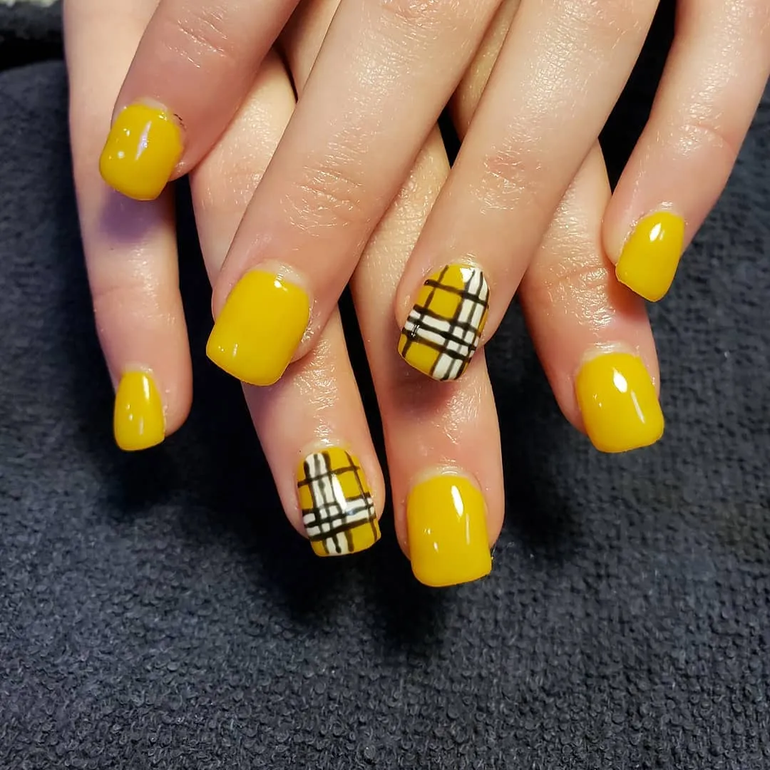 Glossy yellow nails with black-and-white plaid accents