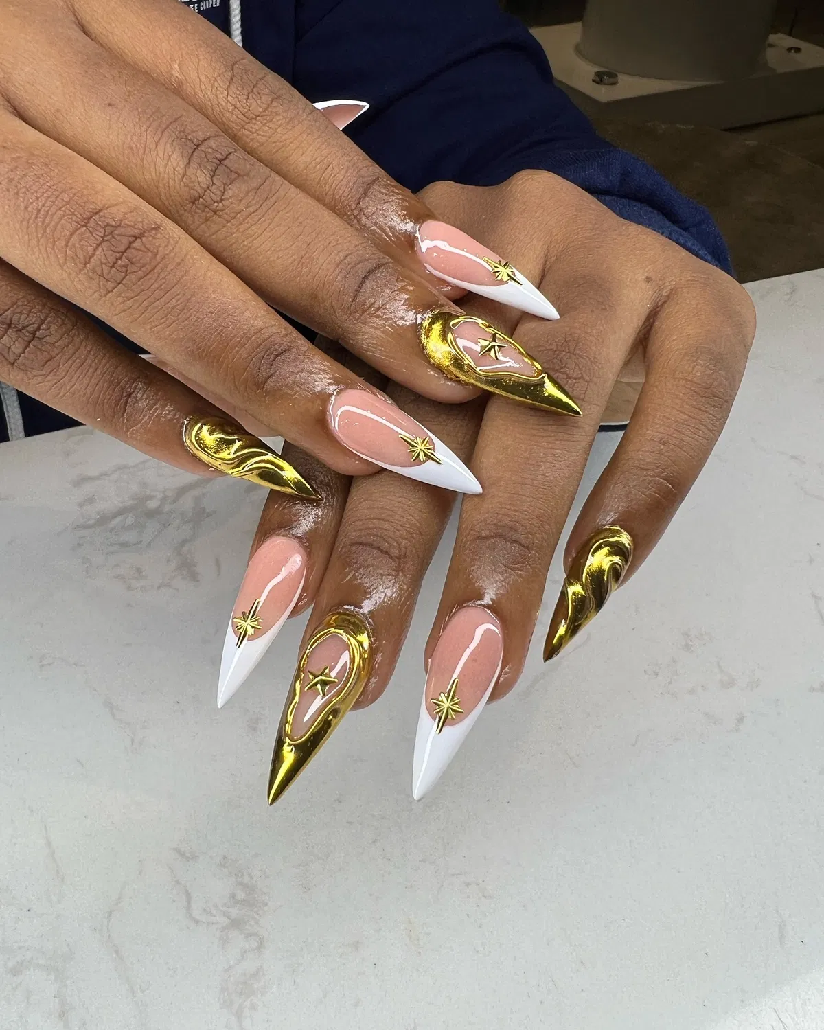 White stiletto tips with reflective gold and starbursts