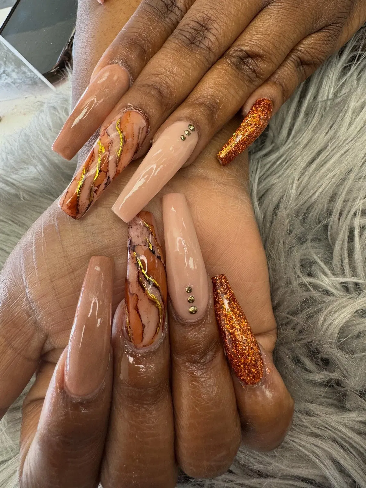 Nude coffin nails with orange glitter and gold-veined marbling