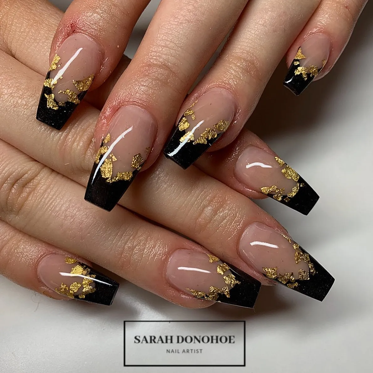 Glossy nude-and-black tips with gold foil flakes