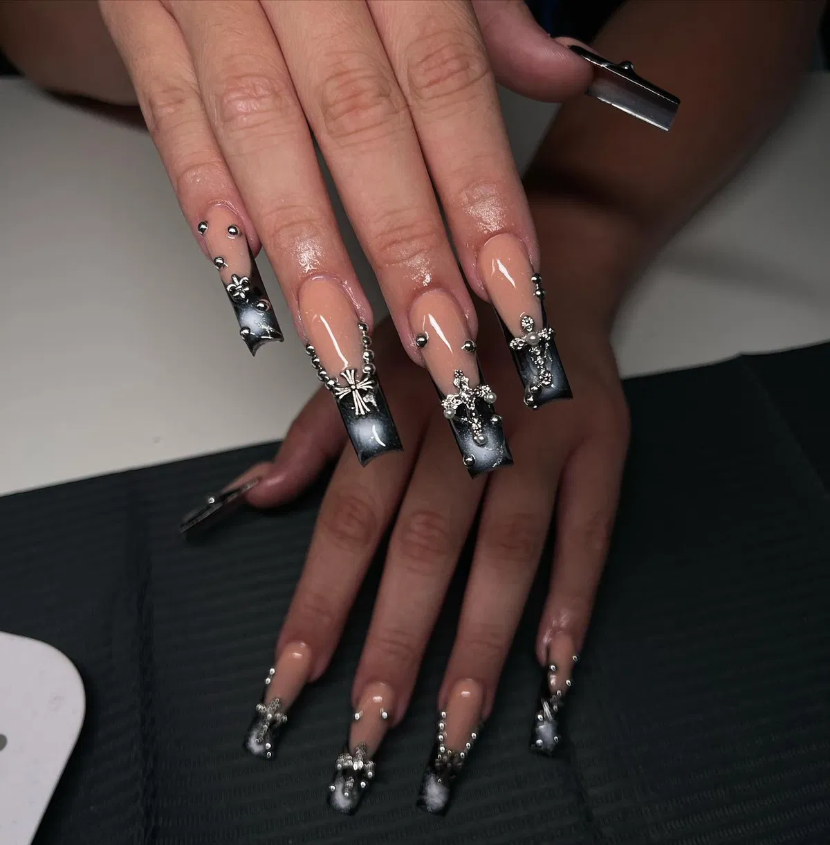 Nude almond nails with black French tips and yin-yang accents