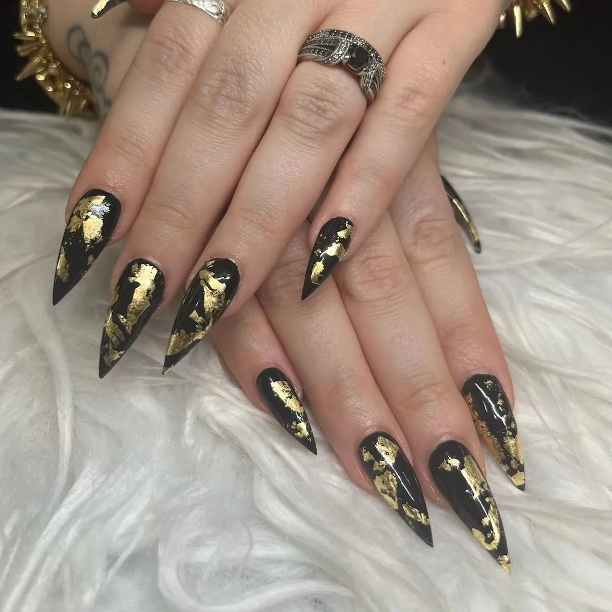 Black stiletto nails with irregular gold foil-like patches