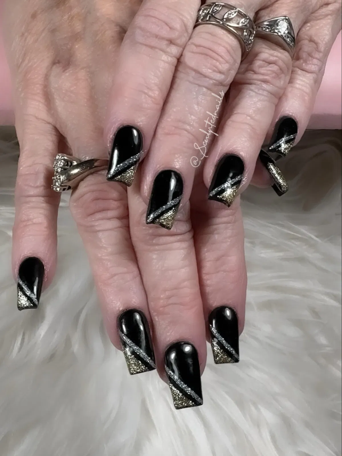 Glossy black square nails with diagonal silver and gold glitter accents