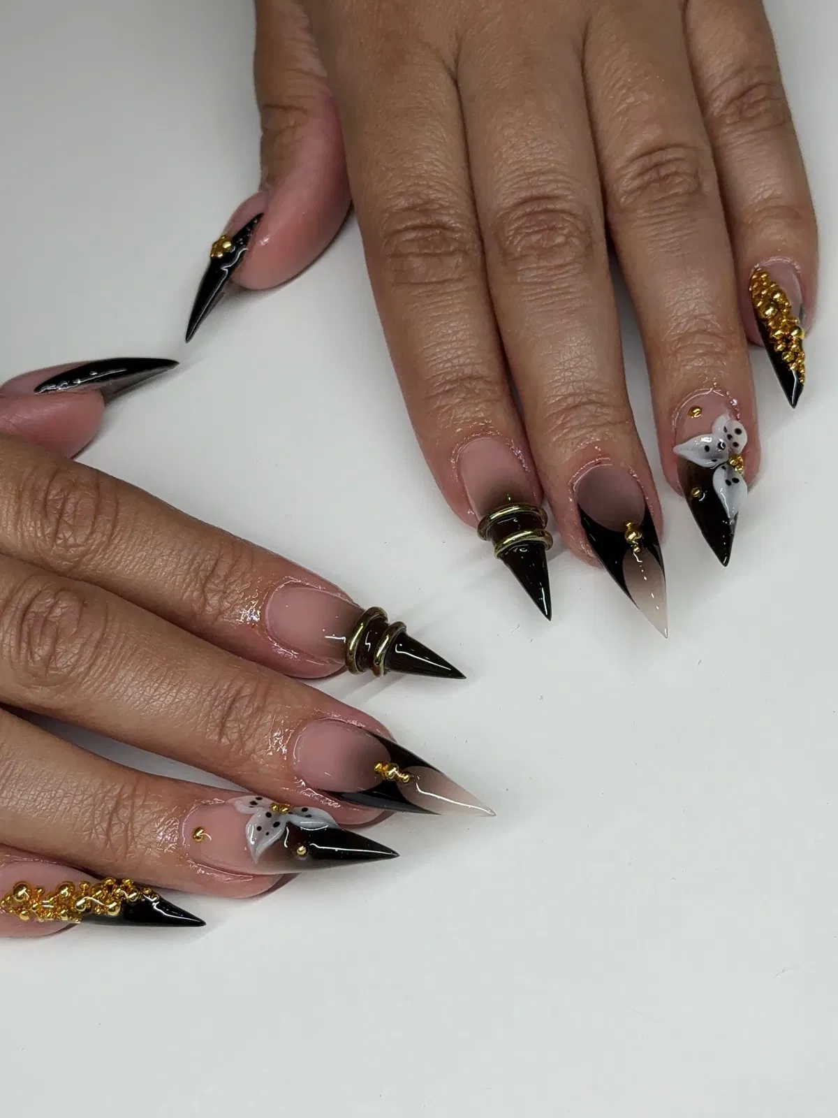 Black-tipped stilettos with clear panels, gold studs, and a white flower accent
