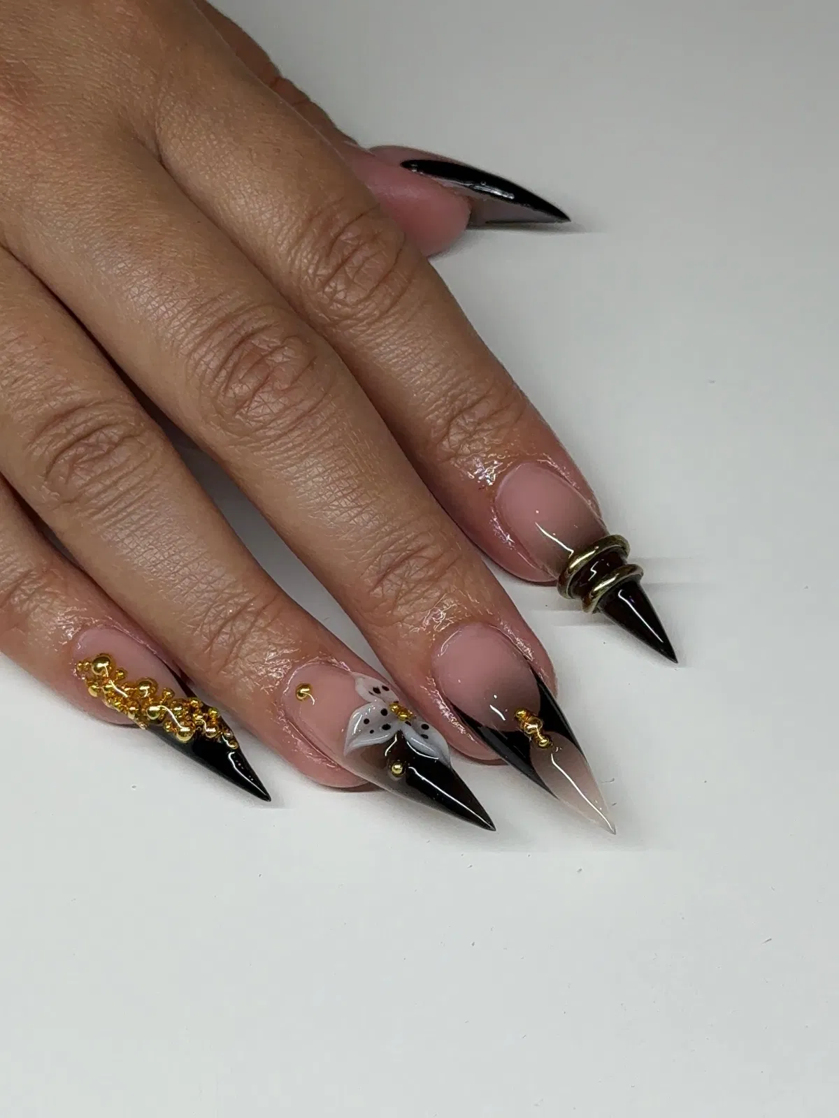 Black-tipped stilettos with gold studs and a white flower accent