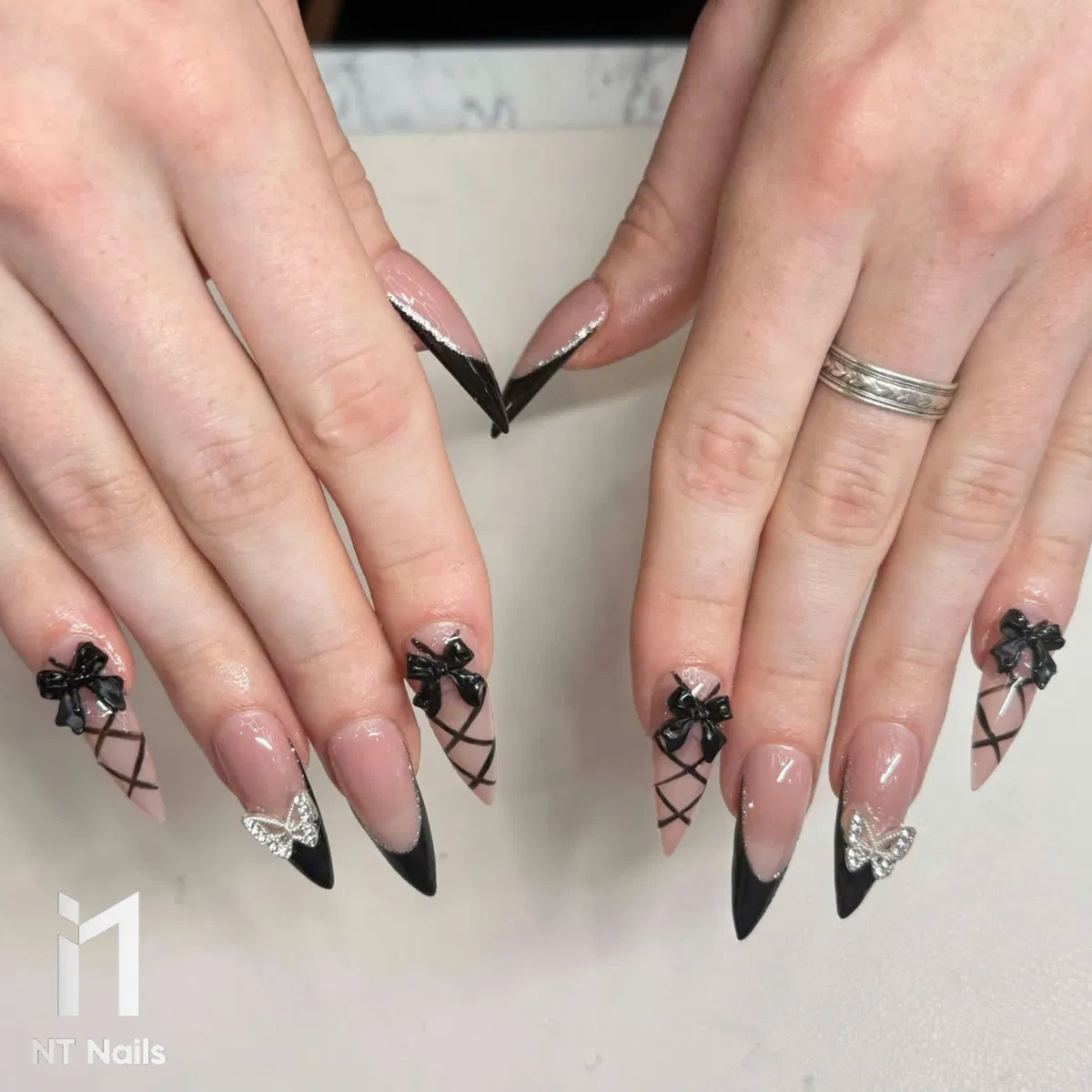 Stiletto black tips with bows, crisscross lines, and silver butterflies
