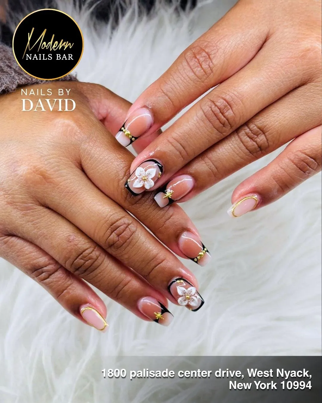 Nude square nails with black tips, gold beads, and 3D white flowers