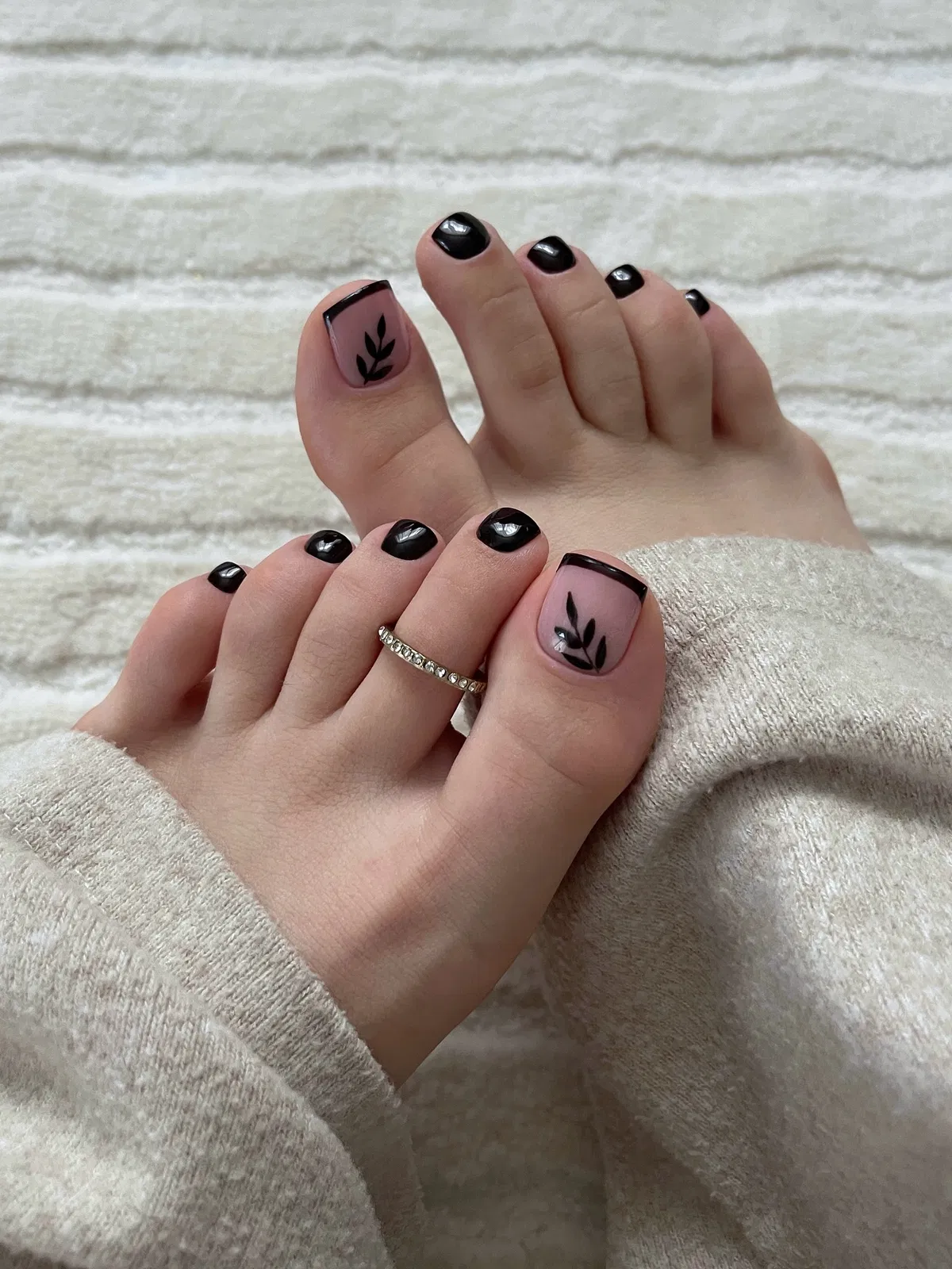 Black pedicure with leaf art on nude big toes