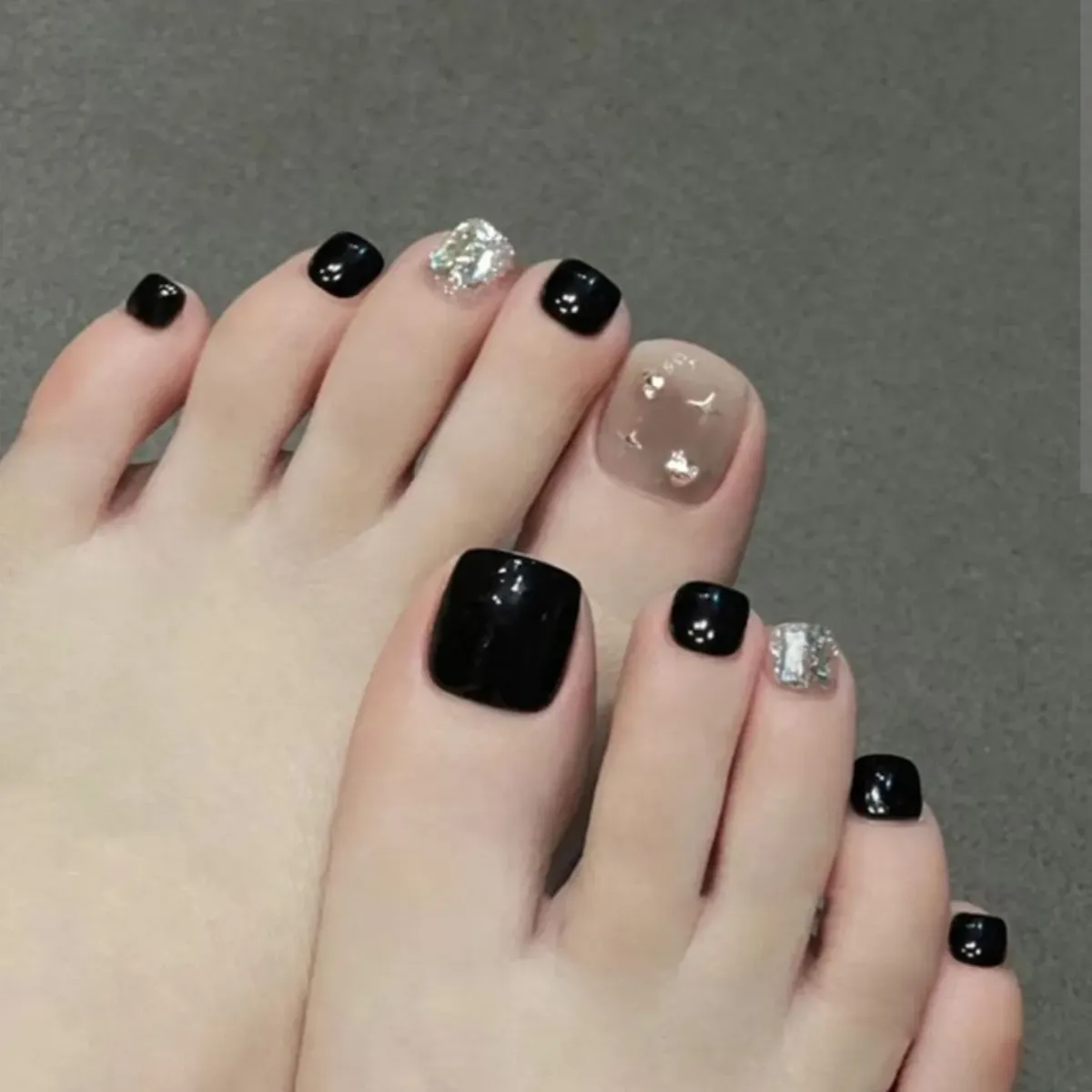 Black pedicure with nude rhinestone big toe and silver glitter accents