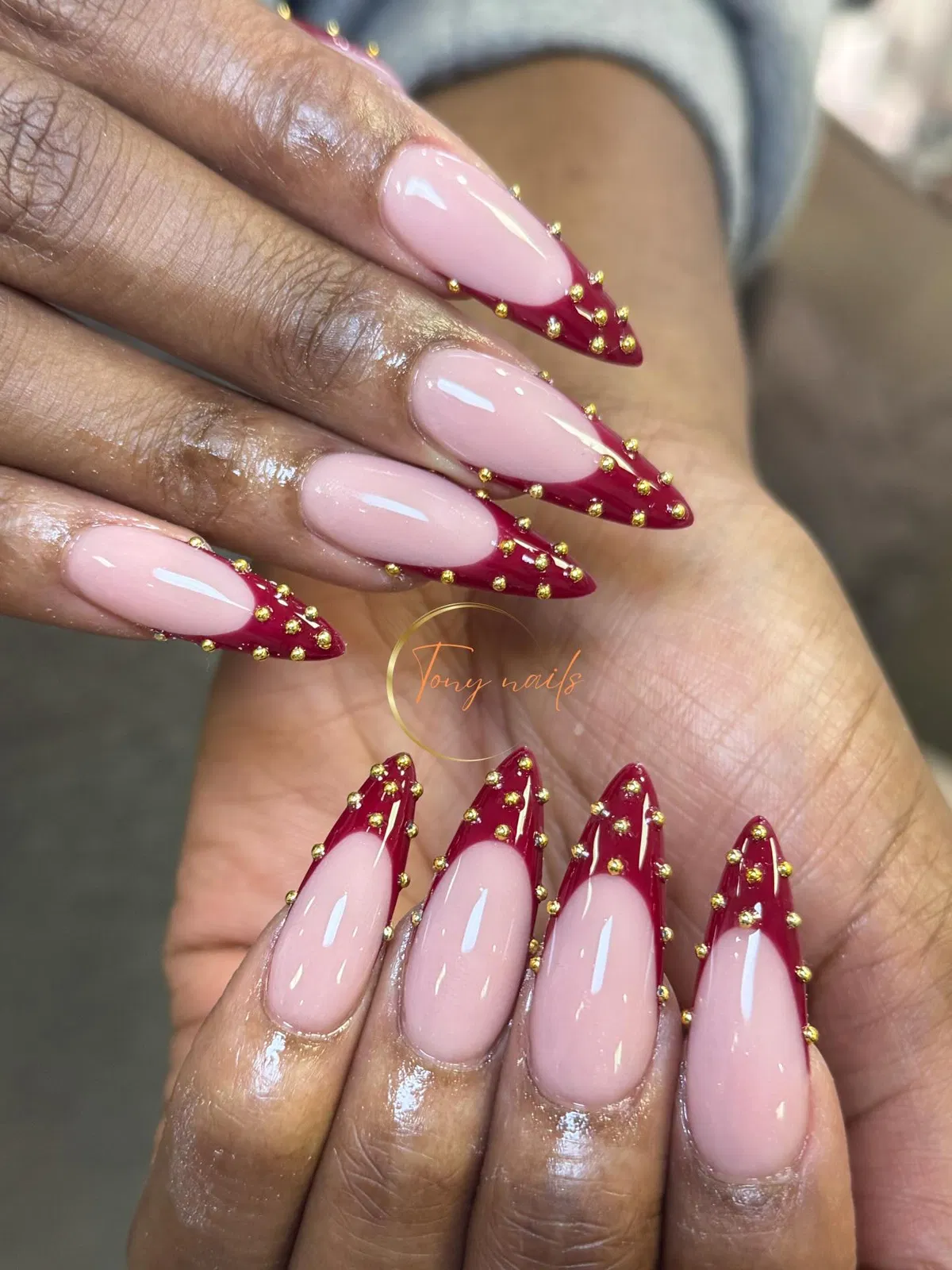 Nude-and-red stiletto French tips with gold studs