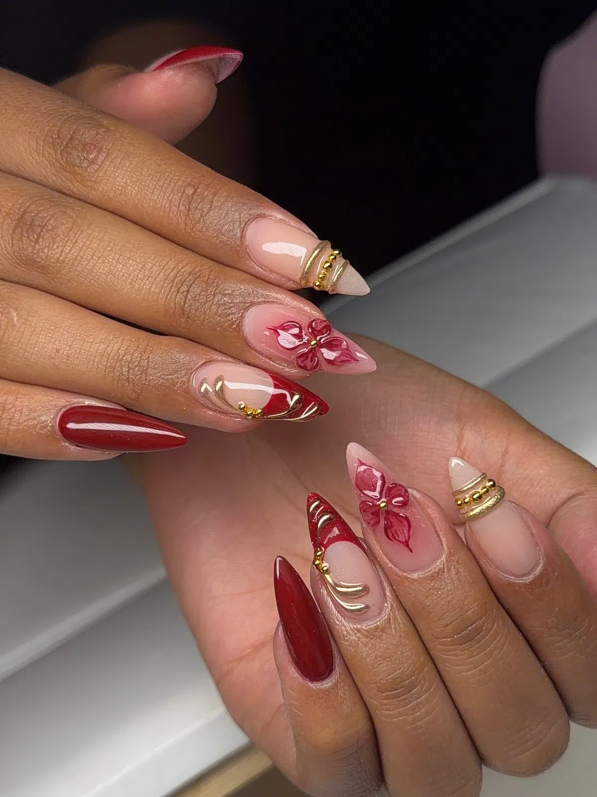 Deep red and nude-pink set with red tips, floral art, and gold accents