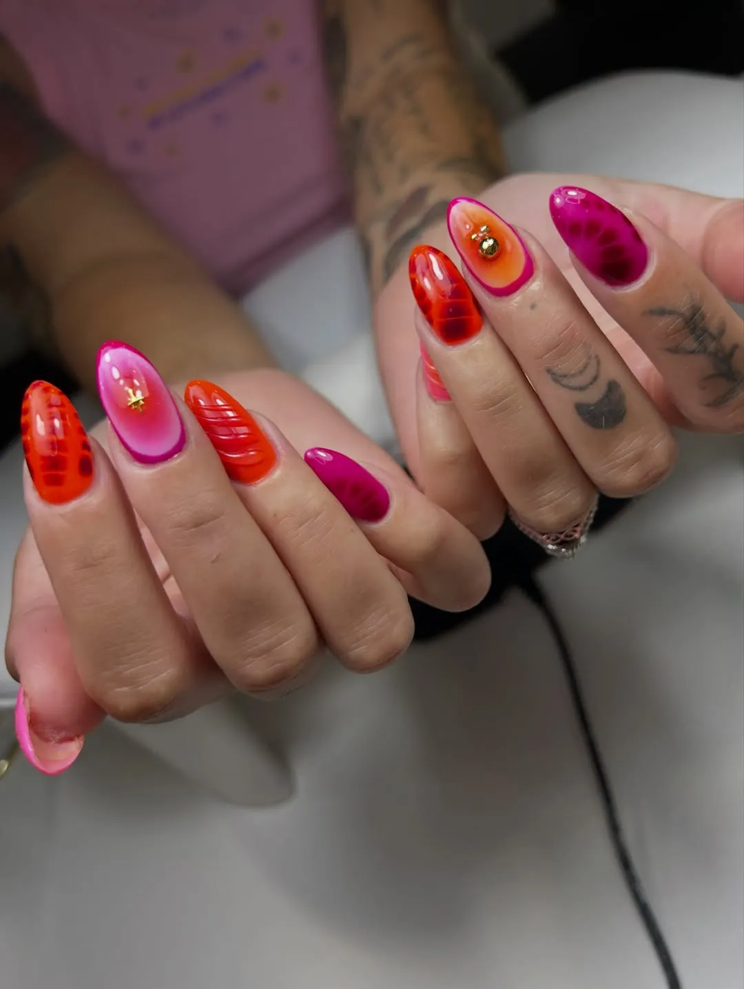 Hot pink and orange-red glossy nails with gold embellishments