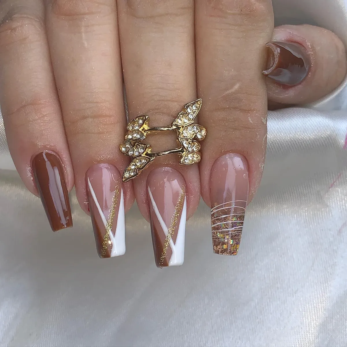 Brown, white diagonals, and gold glitter with a clear glitter accent nail
