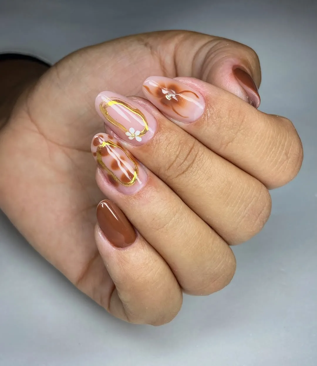 Brown-and-nude marbled swirls with thin gold outlines and a small floral detail