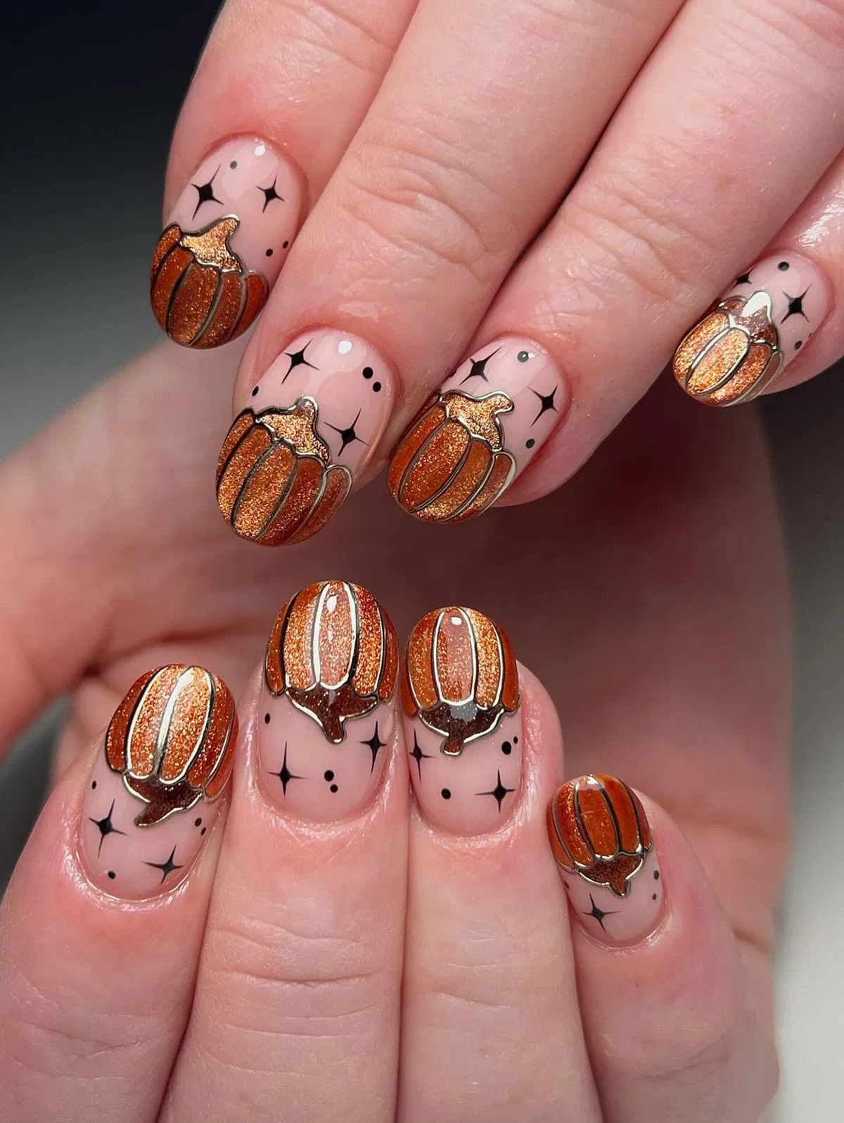 Pumpkin glitter art on nude base with black starbursts