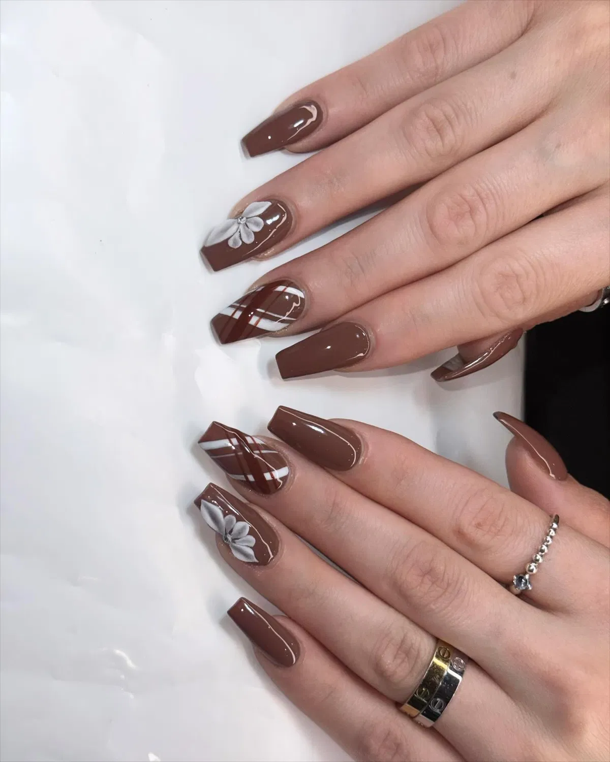Long glossy brown coffin nails with white florals and diagonal plaid