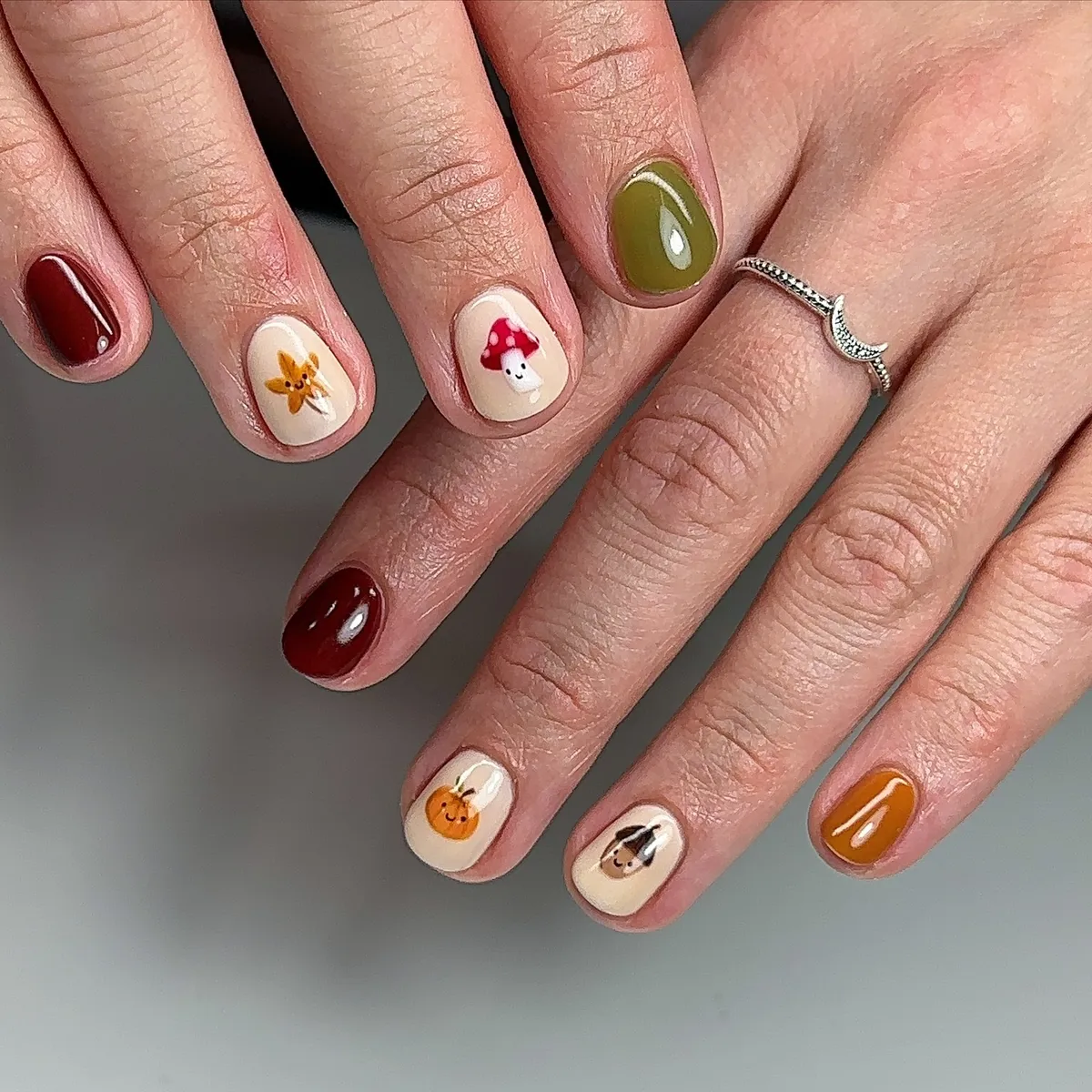 Mixed solids with small illustrated characters on cream nails