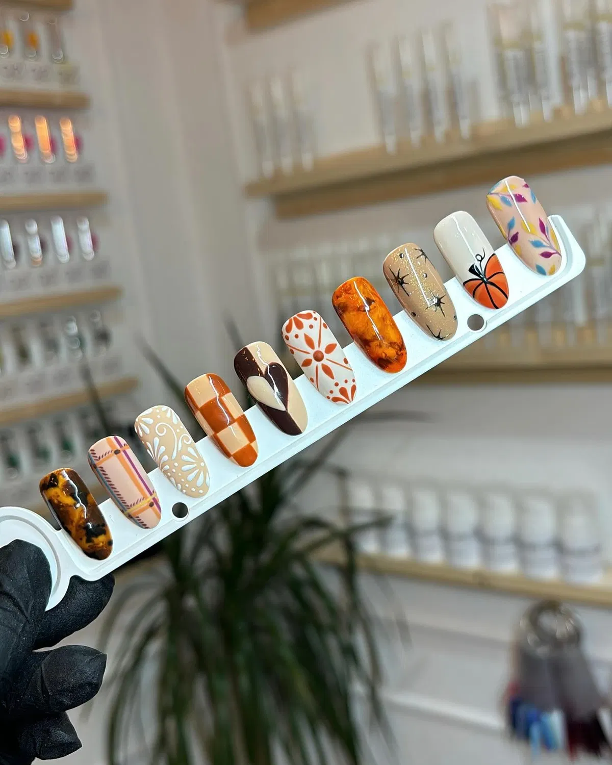 Assorted fall-toned nail tip designs on a display stick