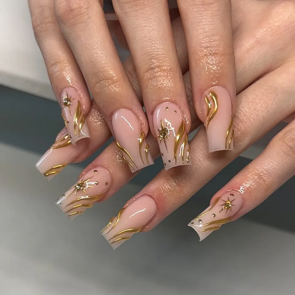 Gold wavy line art with starburst details on square nails