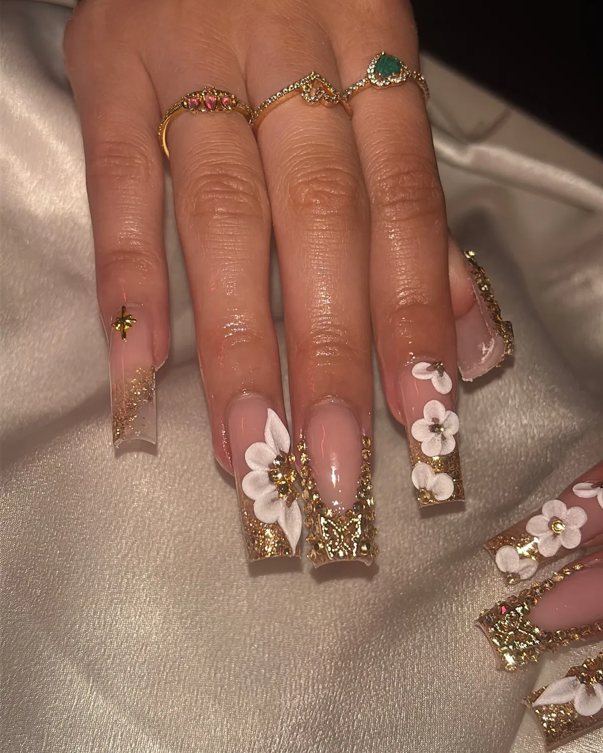 Long square nude nails with gold glitter and white flowers
