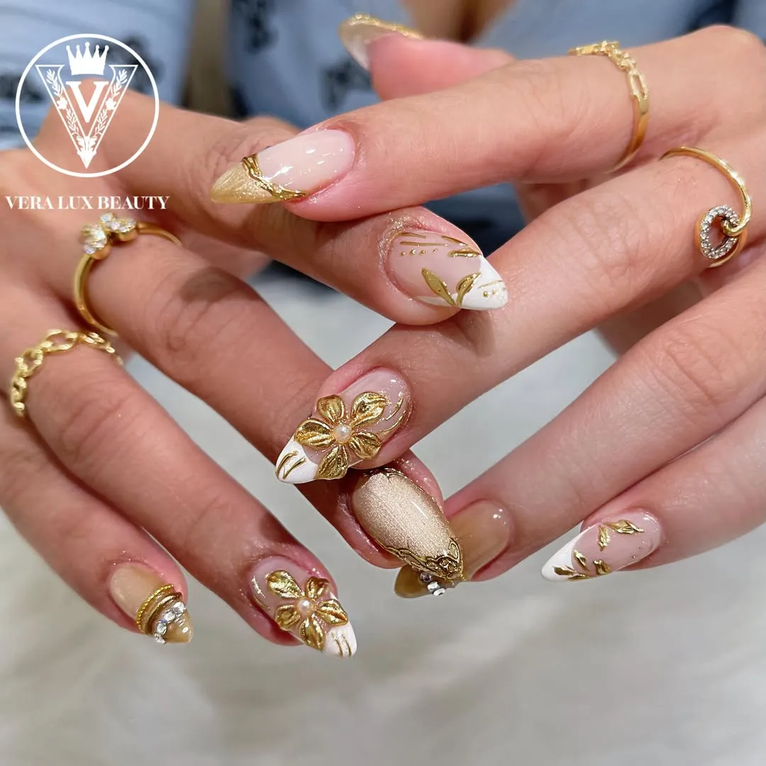 Gold floral embellishments on nude and white nails