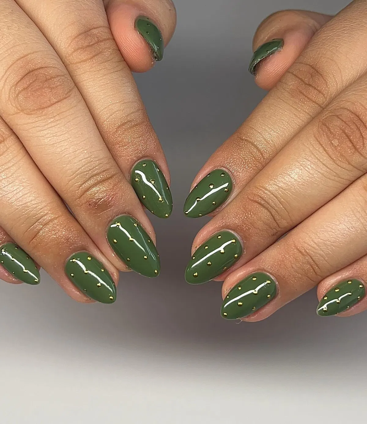 Olive green nails with white waves and gold stud accents