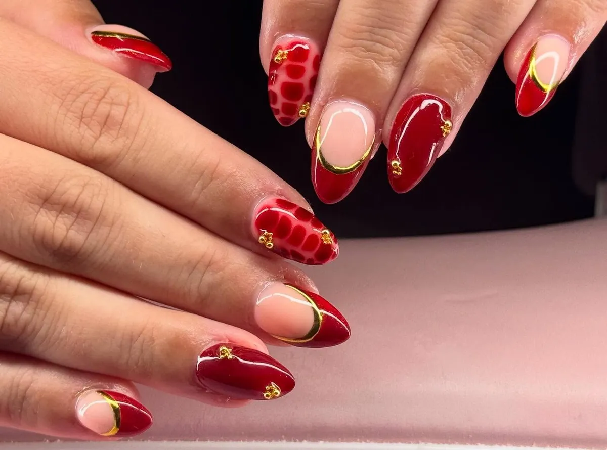Red French tips with thin gold curves and patterned accents