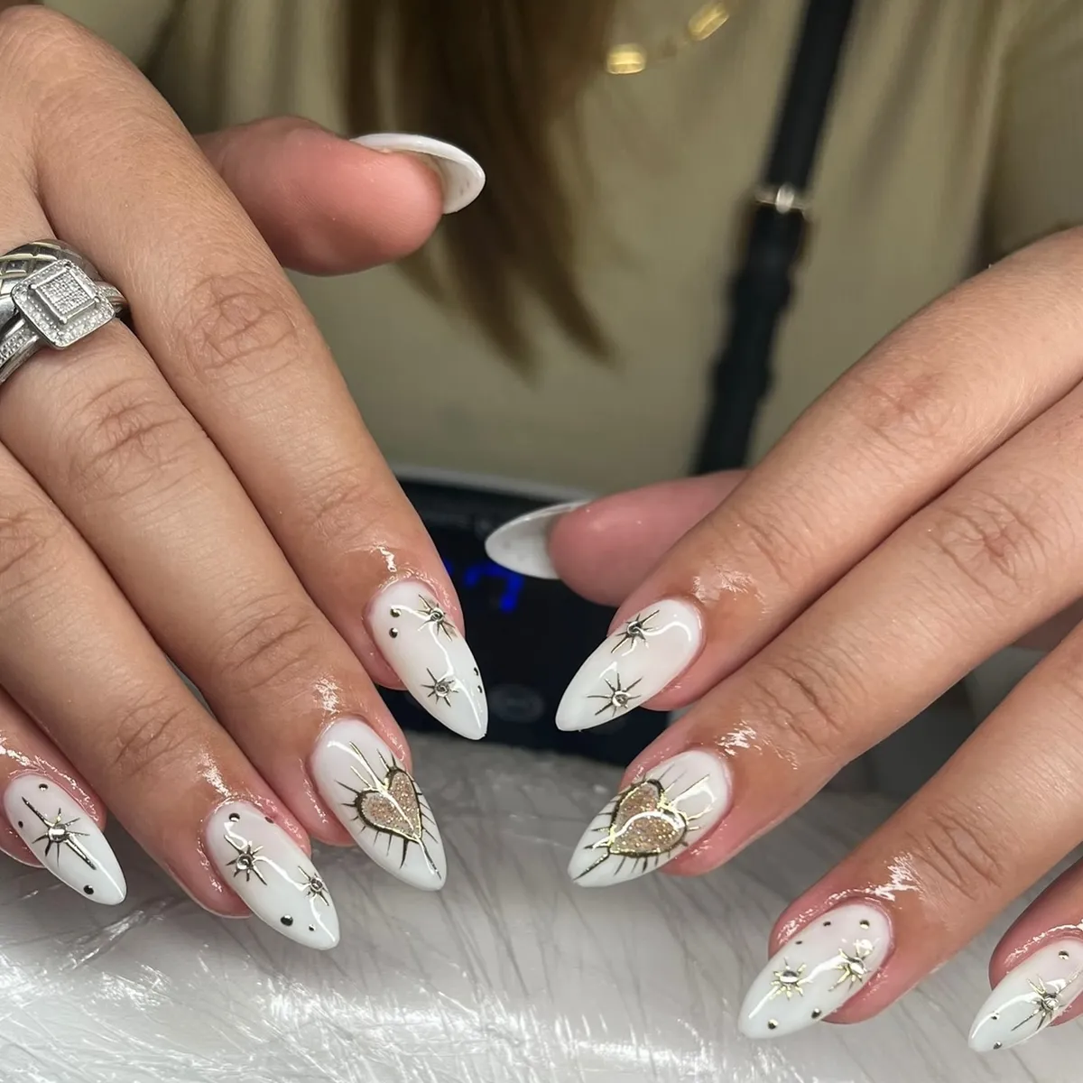 White almond nails with gold hearts and starbursts