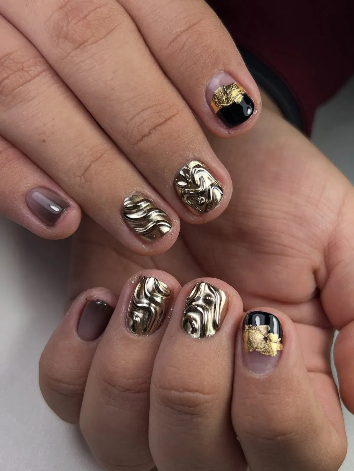 Short nails with raised gold swirls and black-and-gold tips