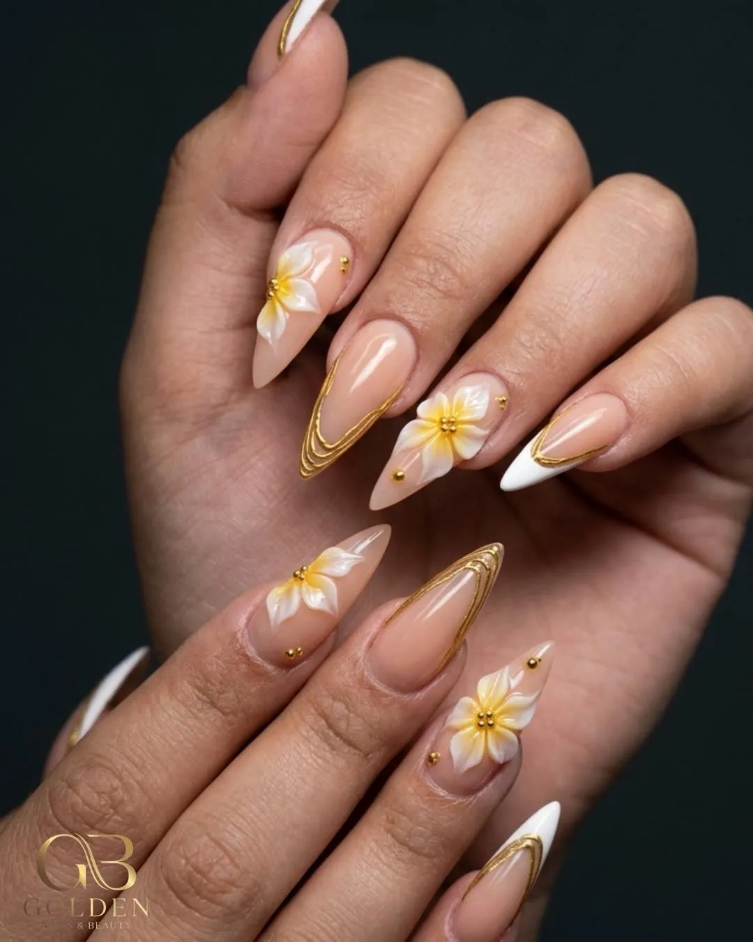 3D white flowers with gold outlines on nude almond nails