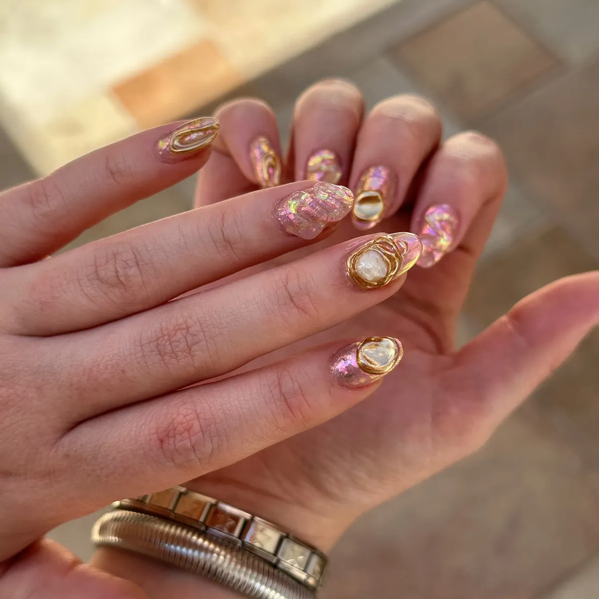 Iridescent pink nails with raised gold oval accents