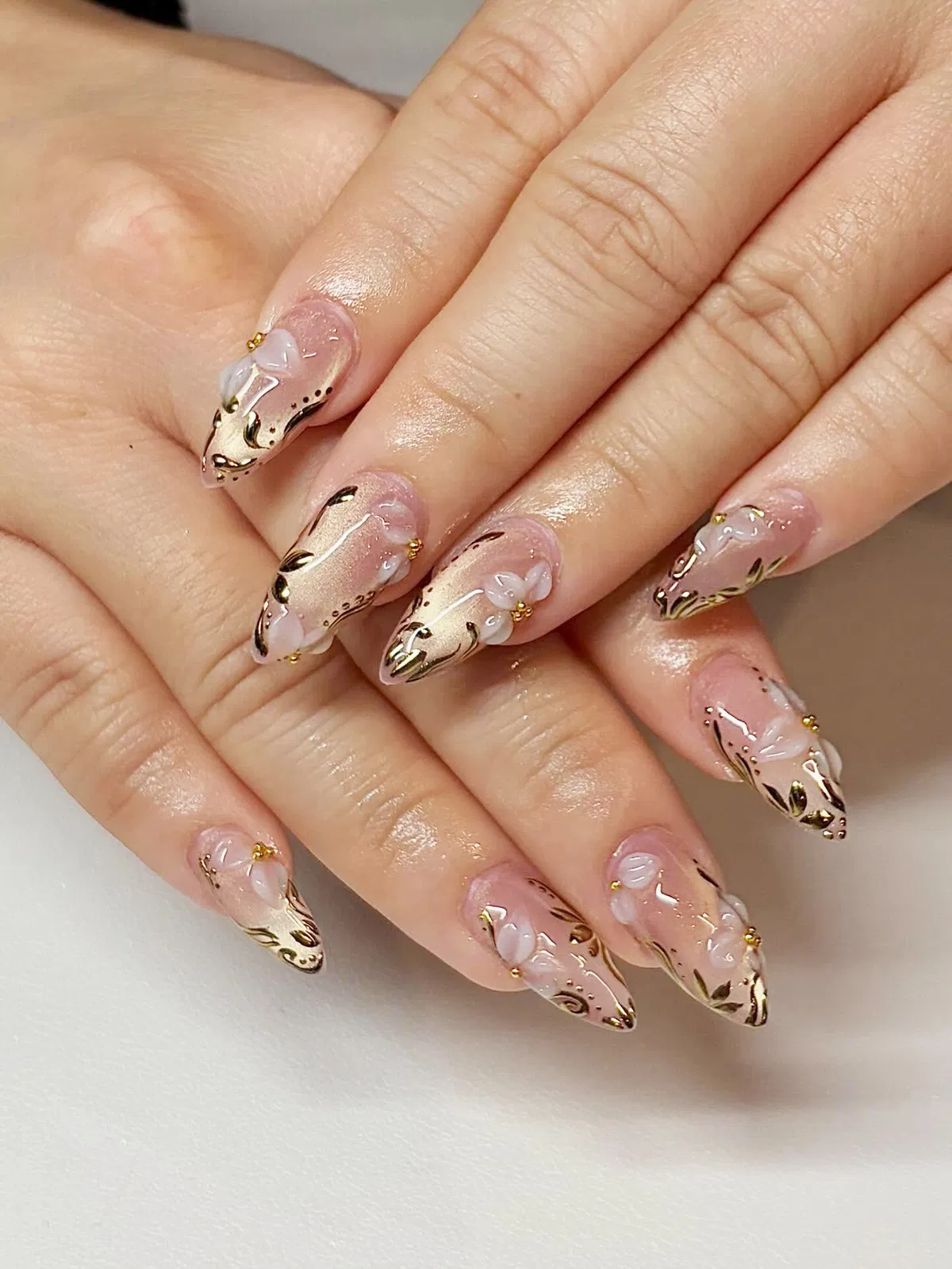 Pointed Nude-Pink Nails with Gold Swirls and 3D Translucent Flowers