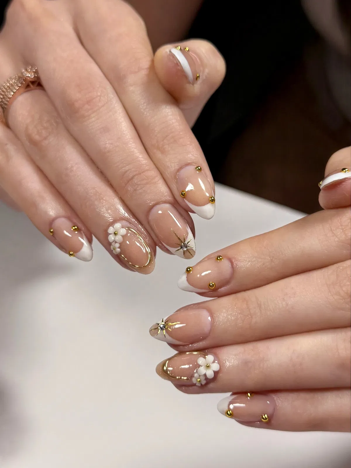 White French tips with gold studs and floral accents