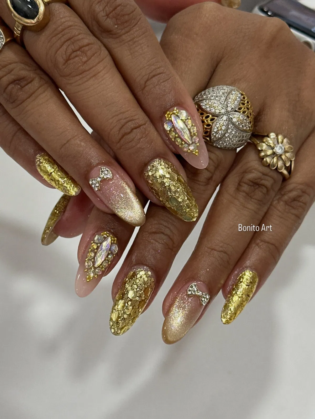 Chunky gold glitter almond nails with bow and rhinestone cluster accents