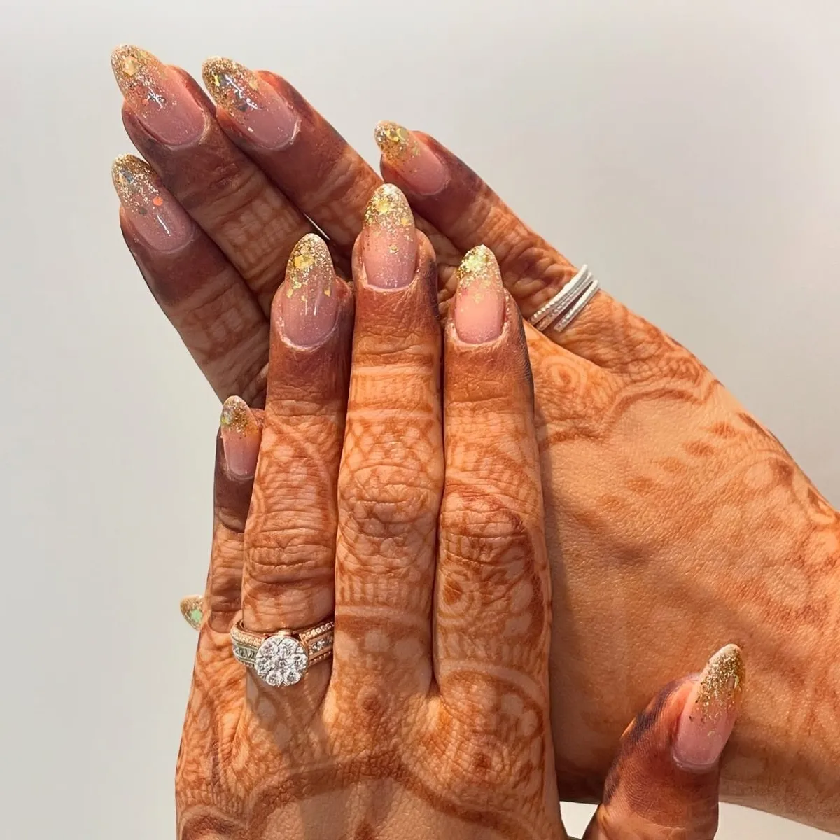 Sheer nude almond nails with scattered gold glitter tips