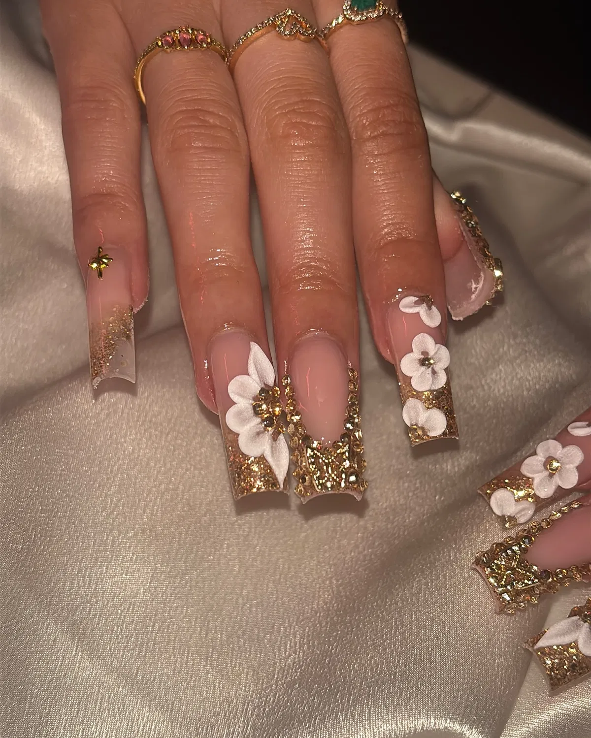 Long square nude nails with gold glitter and white 3D flowers