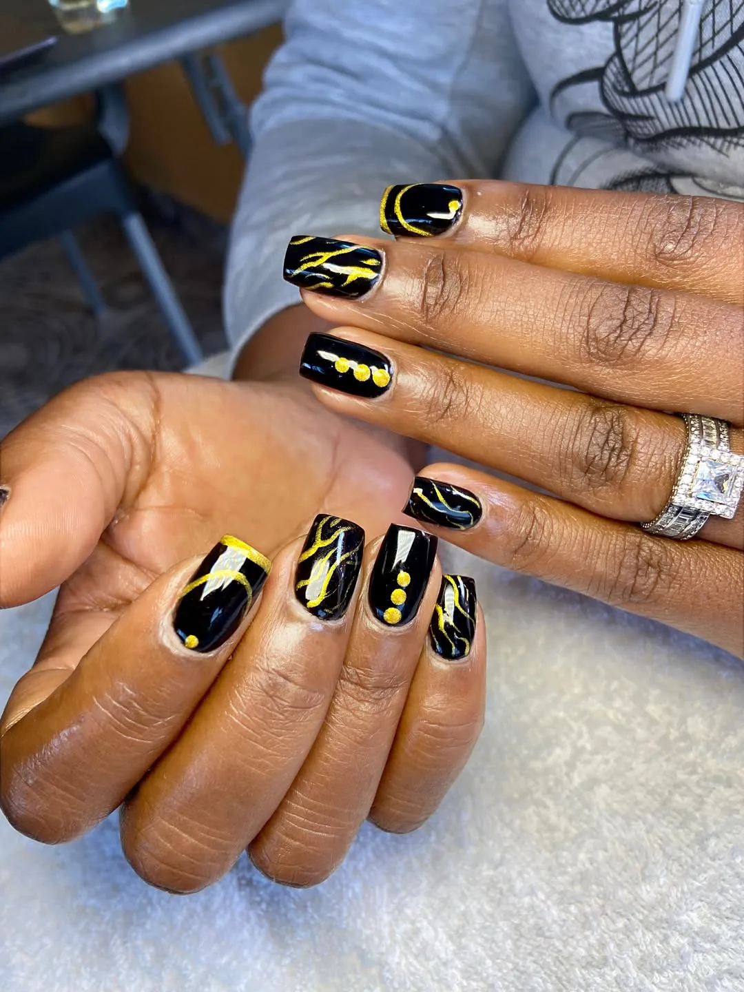Glossy black nails with gold striping and dot accents