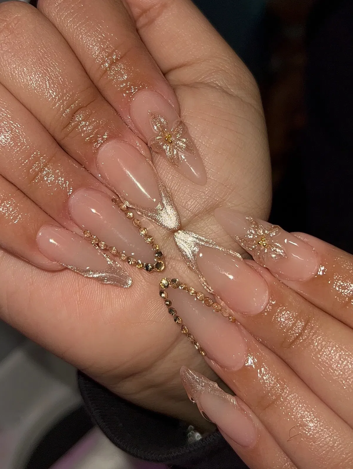 Gold glitter French tips with gem-lined accents and floral detail
