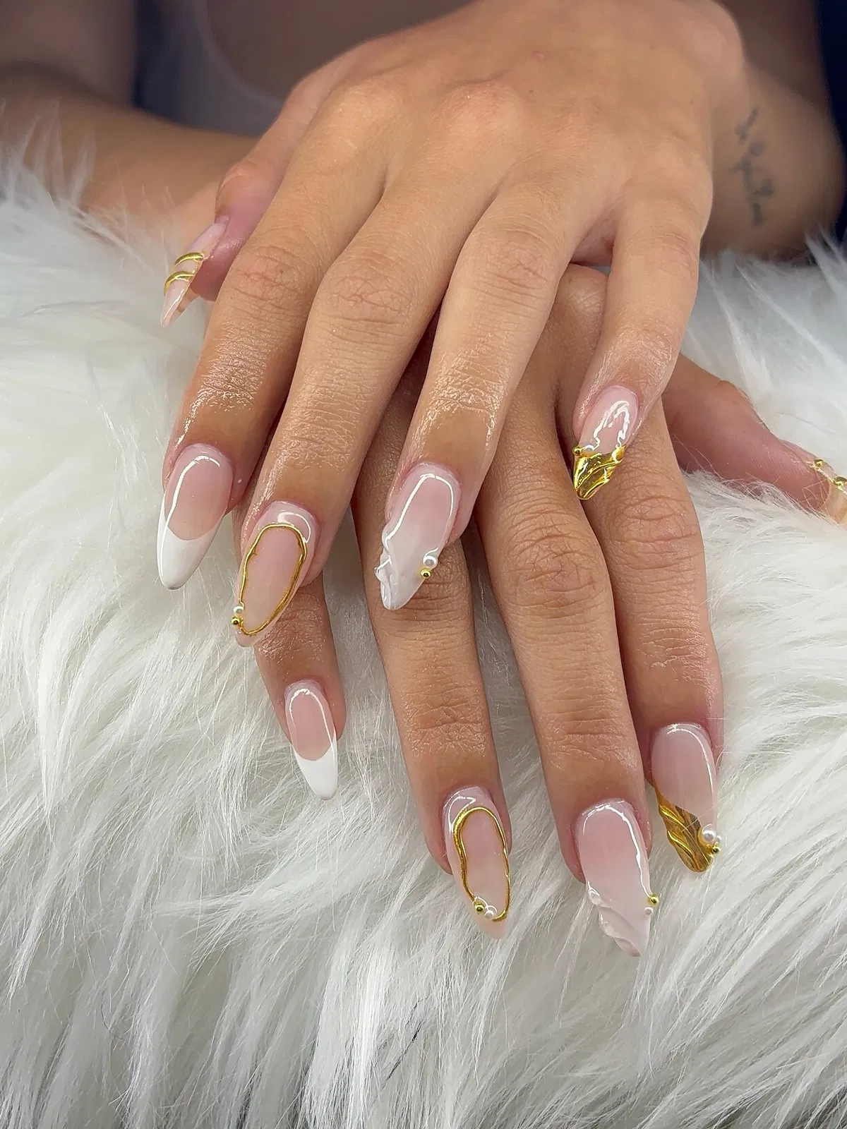 White French tips with gold swirls and pearl-like accents