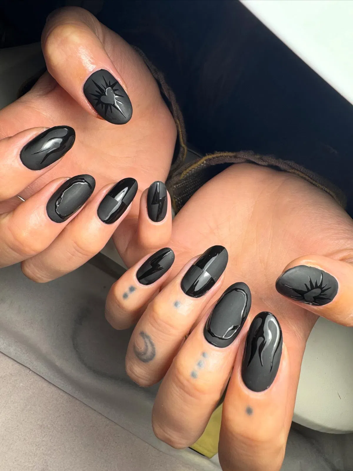 Black nails with heart-and-rays motif and glossy accent shapes