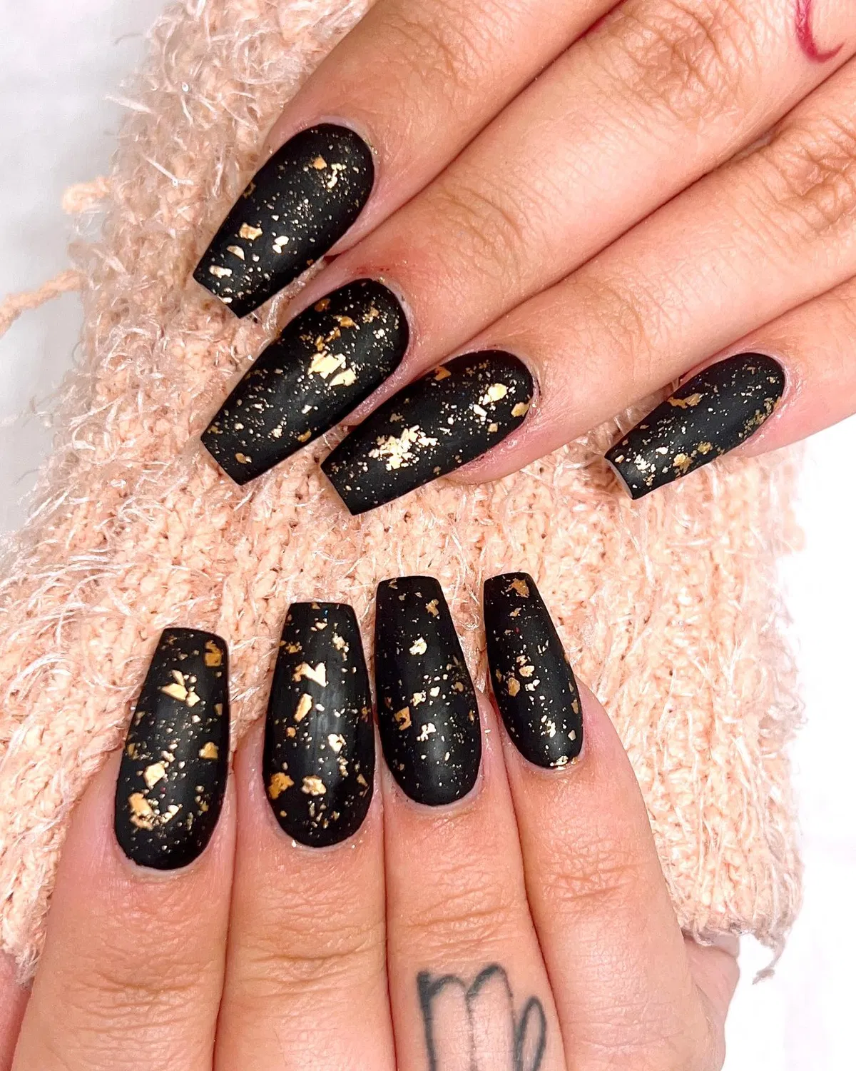 Matte black nails with scattered gold foil flecks