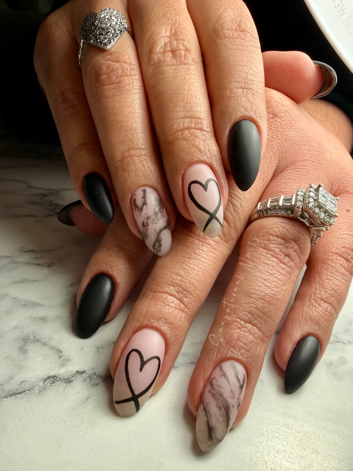Matte black almond nails with heart outline and marbled accents