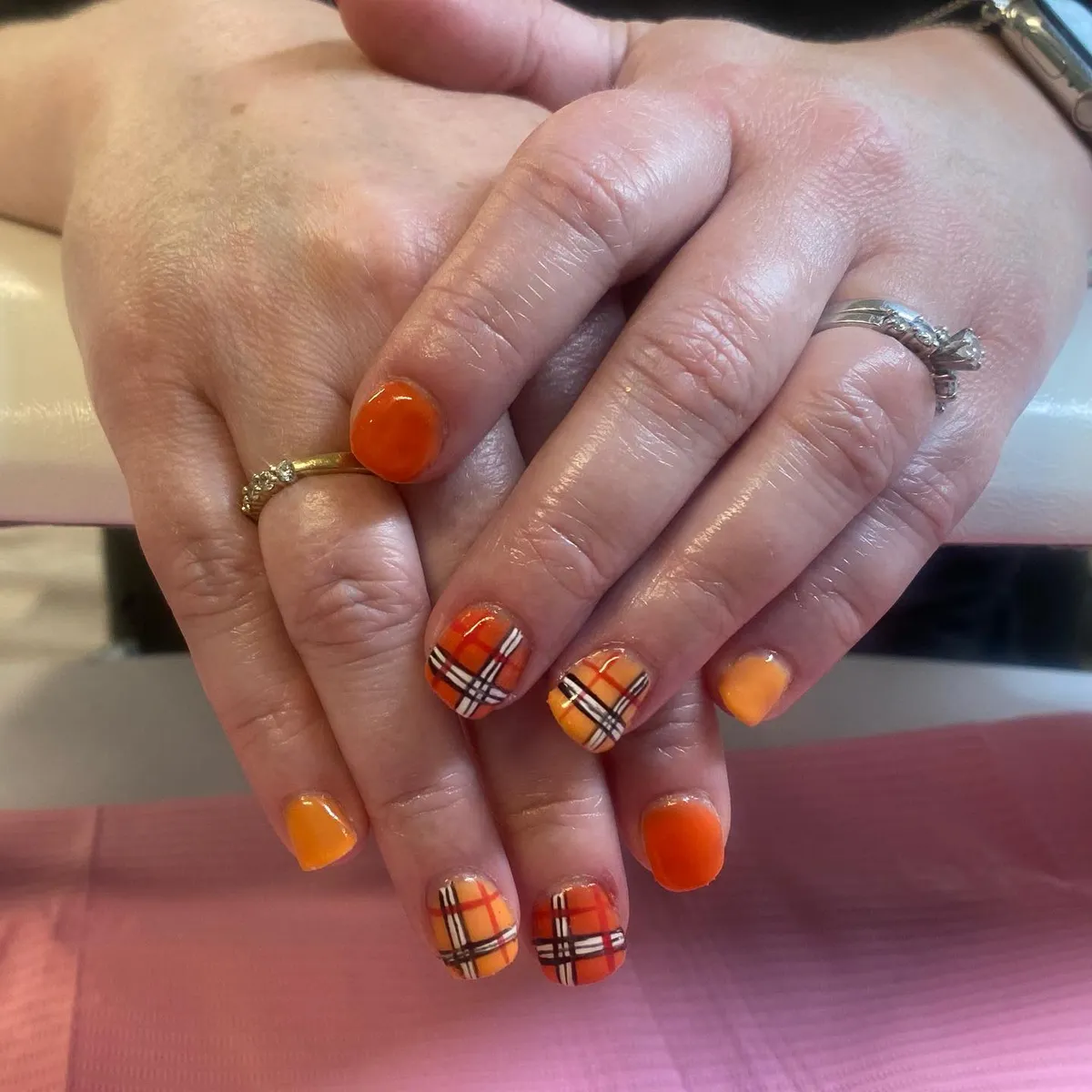 Short orange nails with bold black-and-white plaid