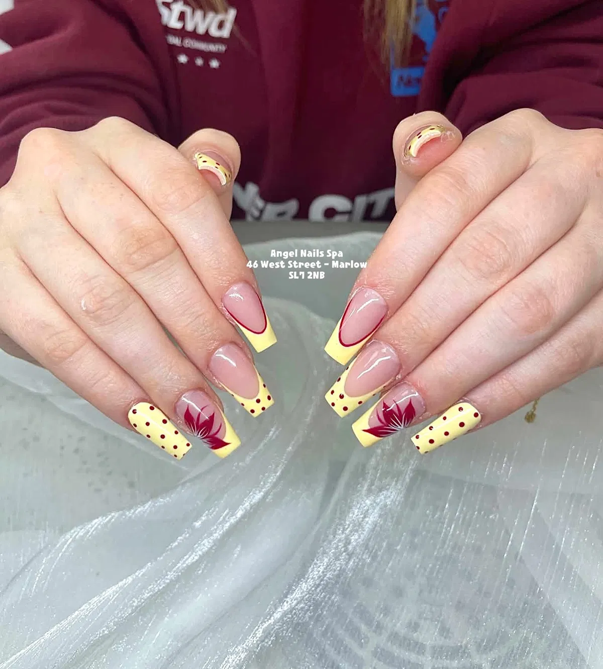 Pastel yellow French tips with red outlines, dots, and leaf motifs
